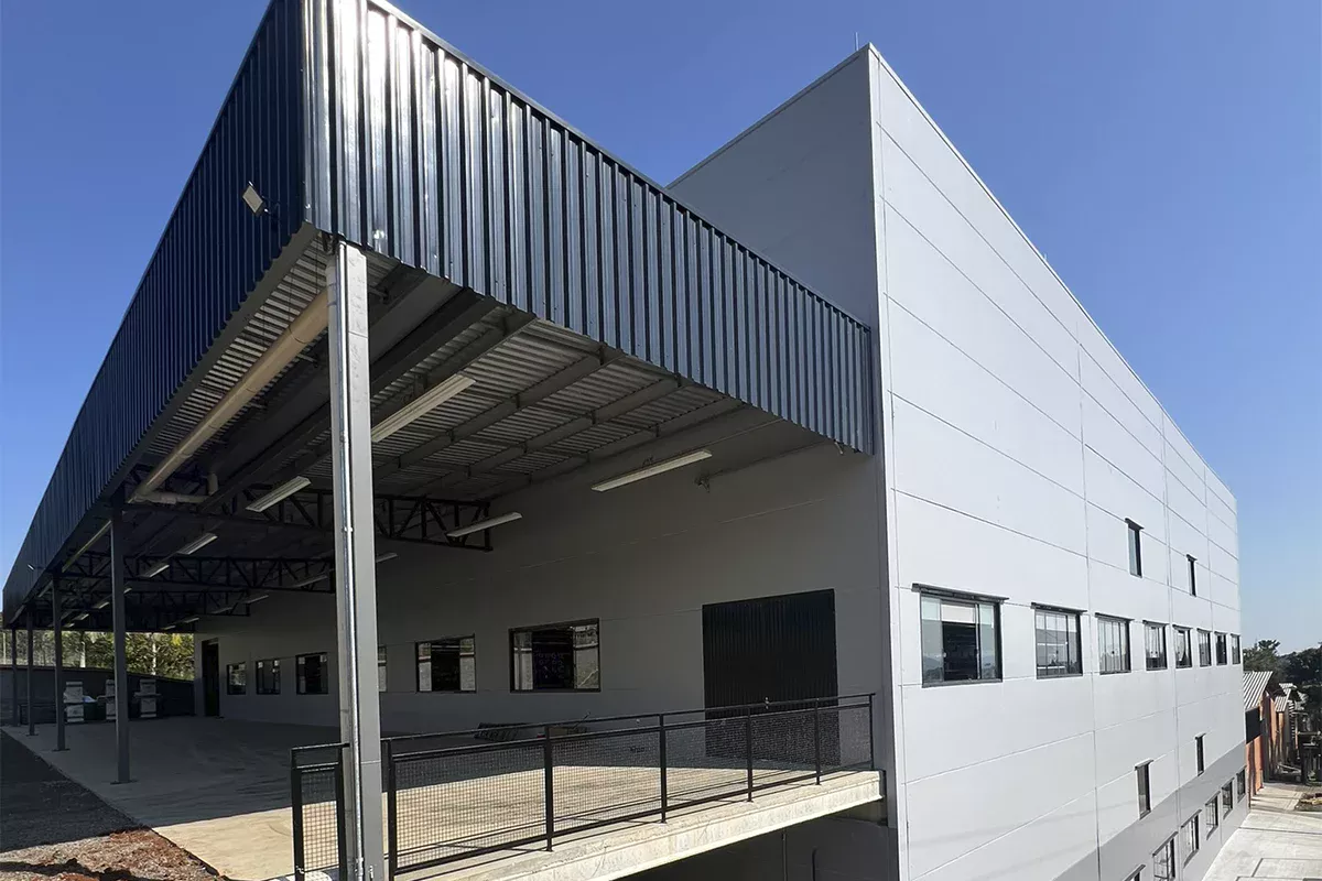 Obras casa Dass - Vista angular do galpão, marquise metálica, plataforma elevada e fachada com acabamento em concreto, mostrando objetividade, funcionalidade e inovação em infraestrutura.