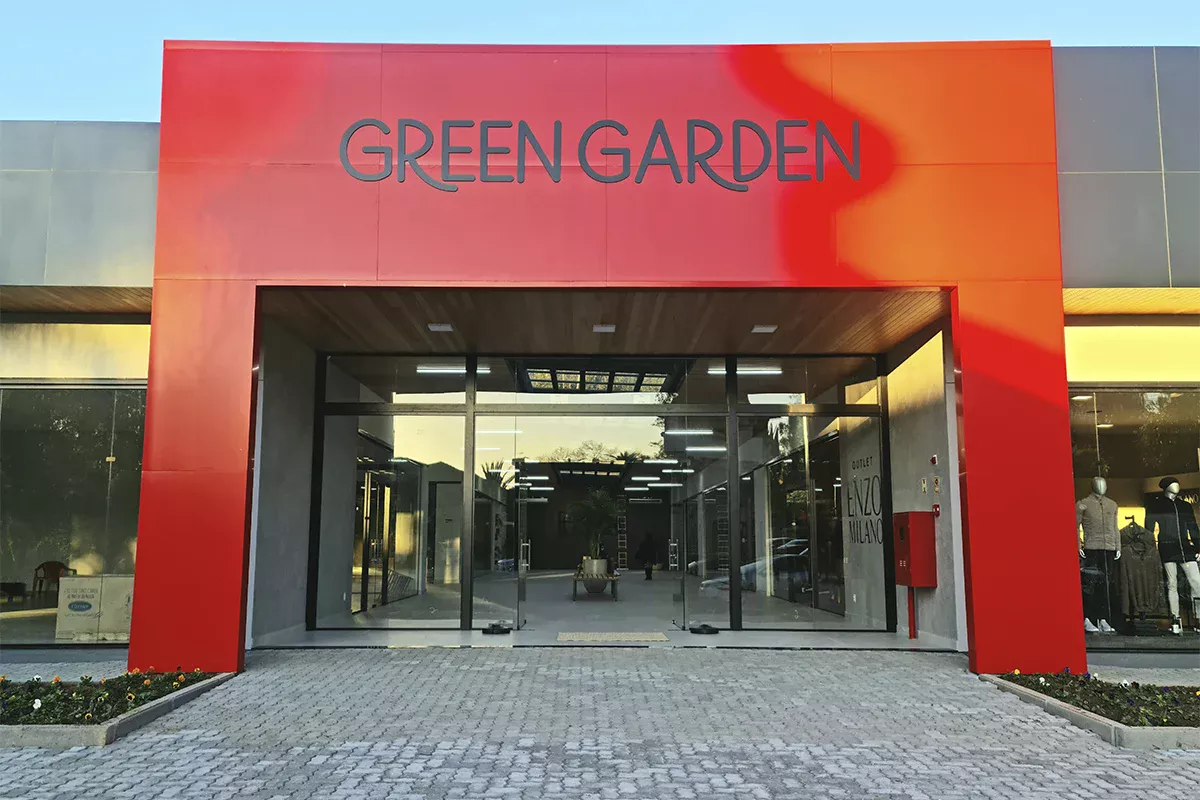 Obras casa Green Garden - Entrada principal do Green Garden, fachada vermelha e portas de vidro, demonstrando atendimento resolutivo, organização e excelência no ambiente corporativo.