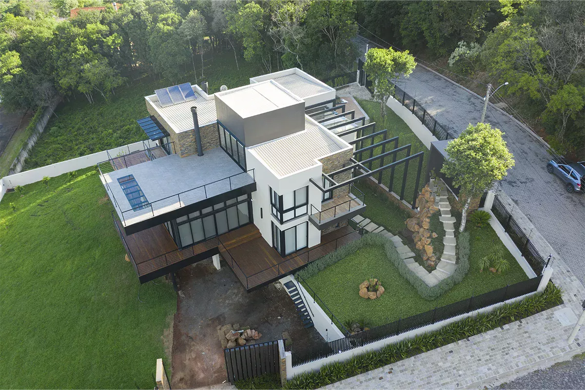 Obras casa MR - Perspectiva superior de casa moderna com dois pavimentos, ambientes integrados, jardim frontal e cercamento, destacando planejamento estratégico e excelência técnica