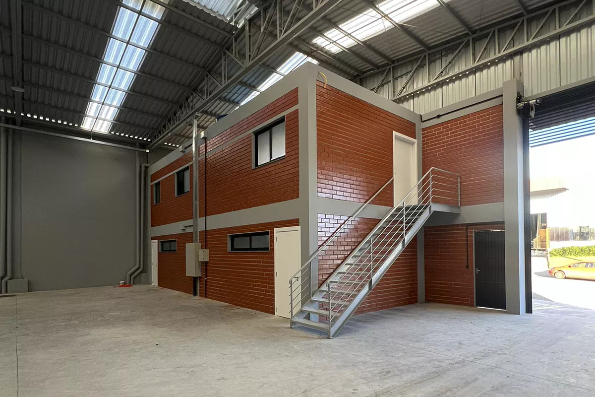 Obras casa Pavilhão Comercial - Área interna do galpão industrial, estrutura metálica aparente, mezanino em alvenaria com escada metálica e ambiente amplo, reforçando expertise técnica, organização e Soluções em Comunicação voltadas à gestão comercial assertiva.