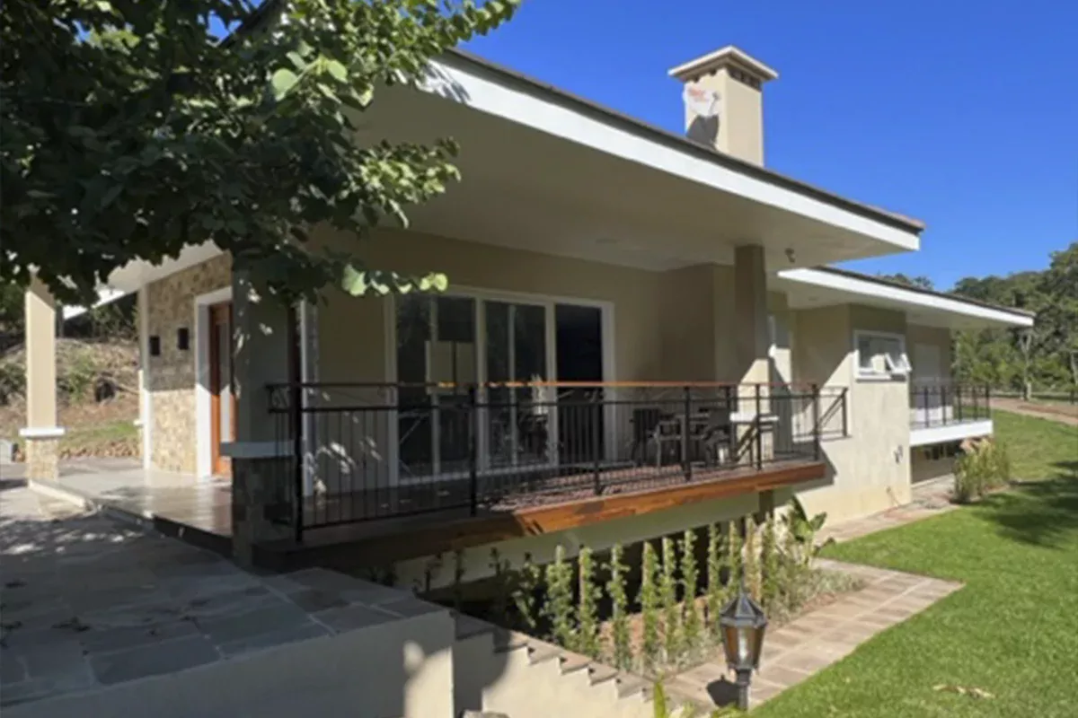Obras casa J+S - Varanda lateral coberta, guarda-corpo em ferro, piso em pedra e vista para jardim, destacando ambientes confortáveis, objetividade e soluções inovadoras em arquitetura residencial.